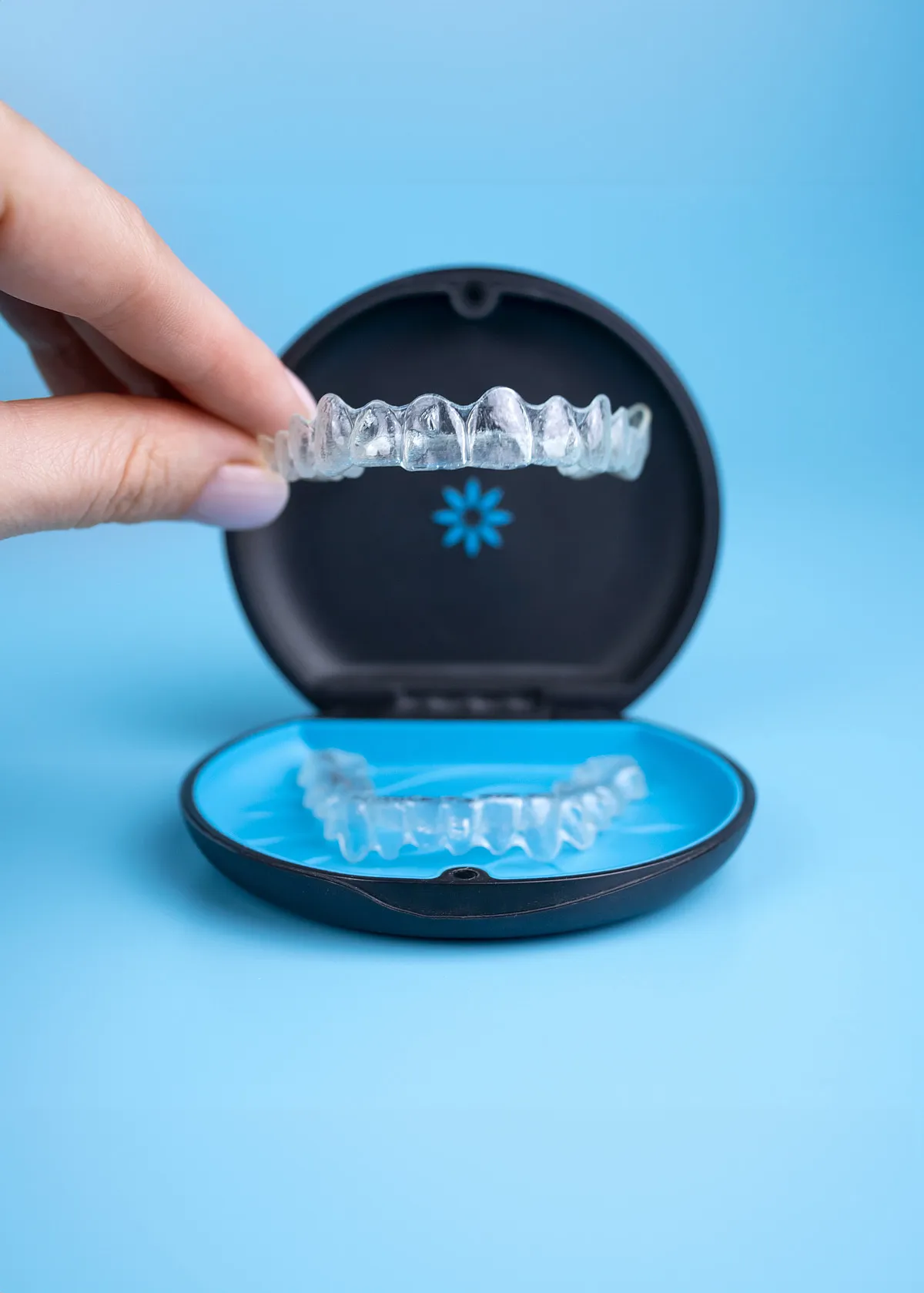 A clear aligner tray being lifted out of its storage case