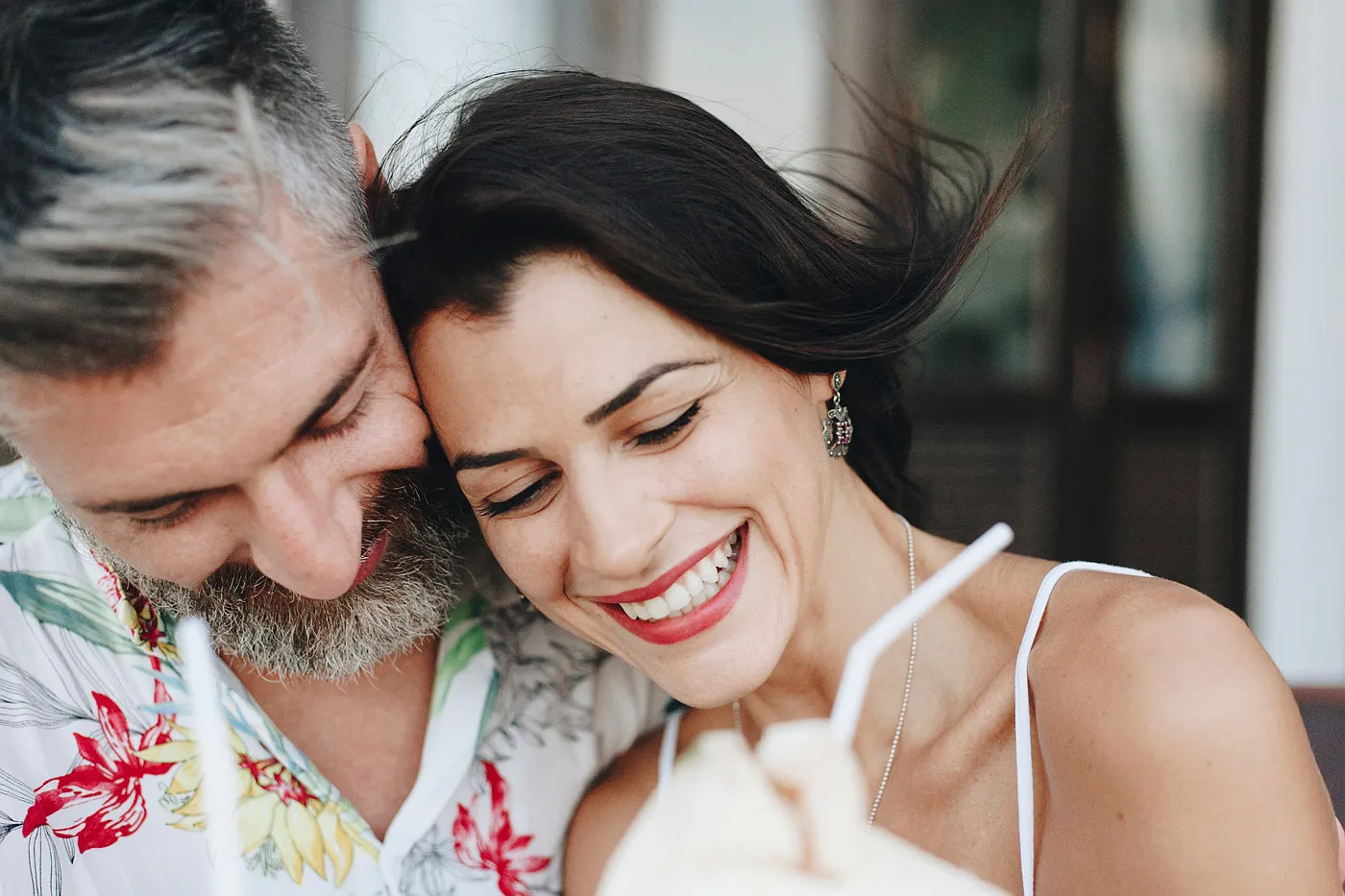 A couple resting cheek to cheek, the woman laughing with an open smile