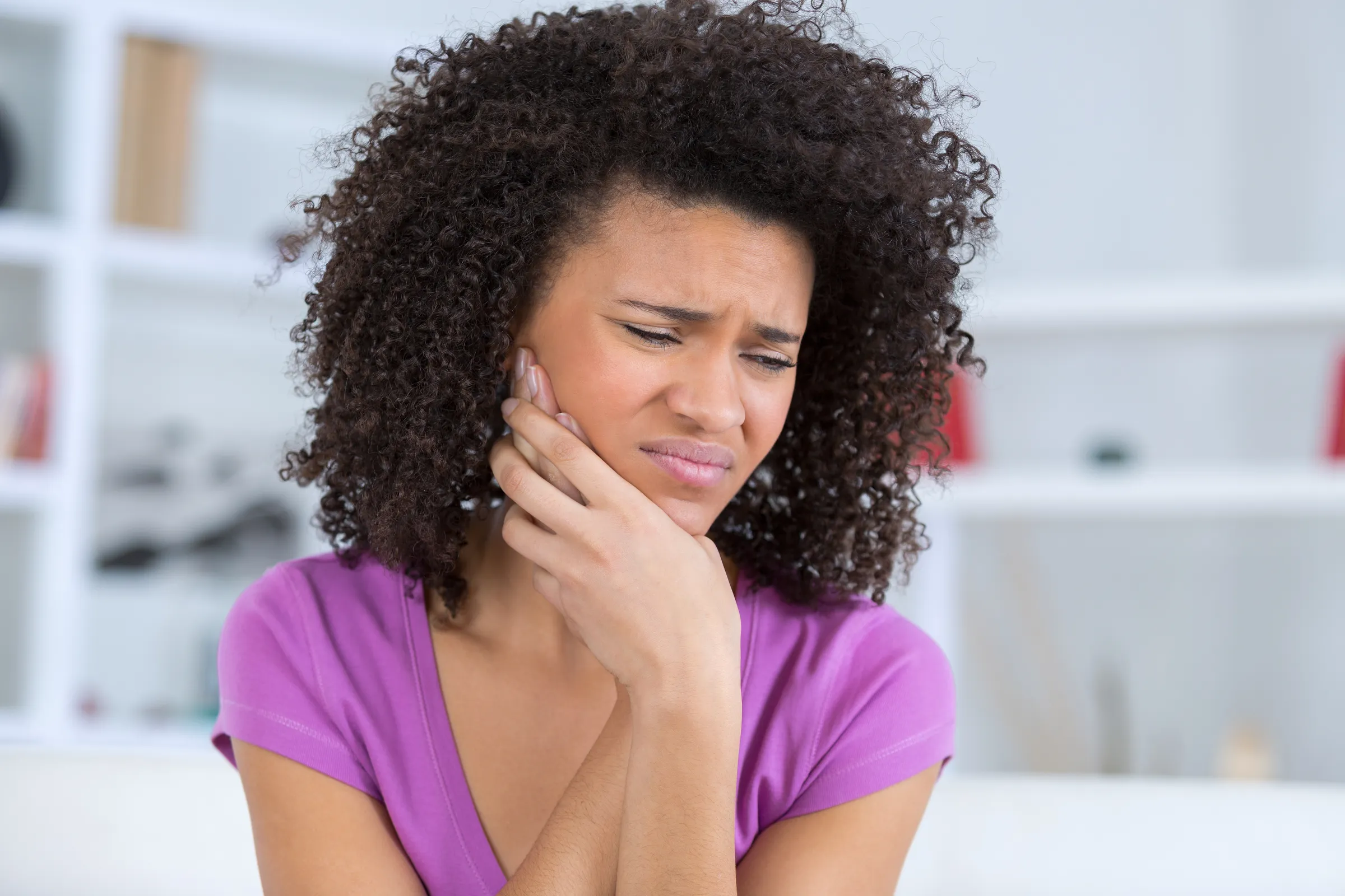 A woman holding her jaw in pain