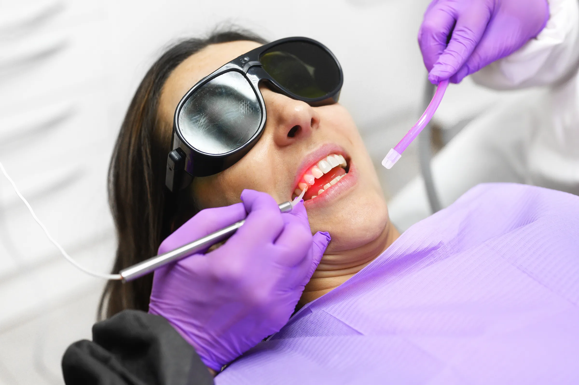 A patient wearing protective eyewear during laser gum treatment