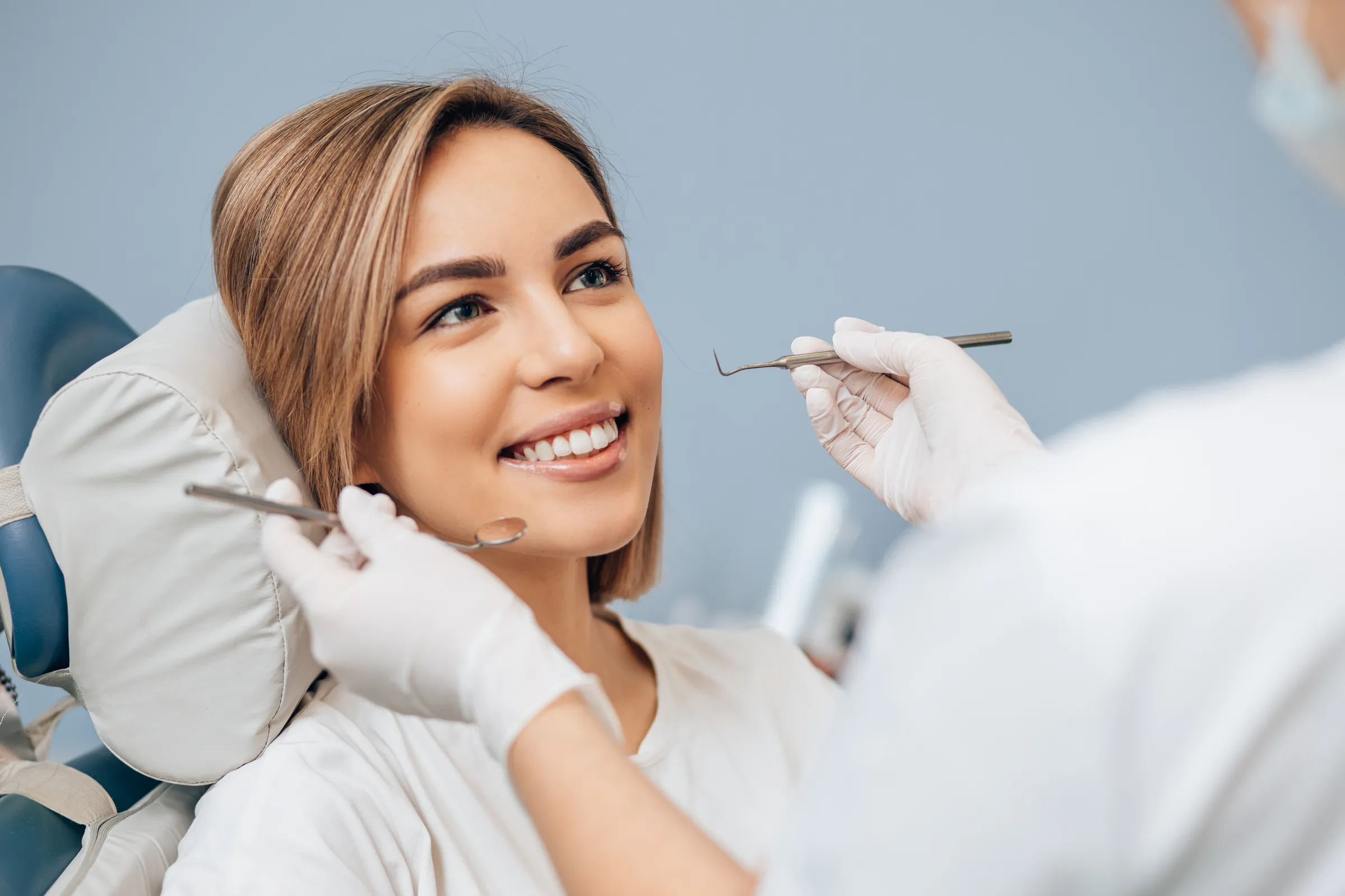 A smiling patient reclining in the chair as the dentist begins an examination