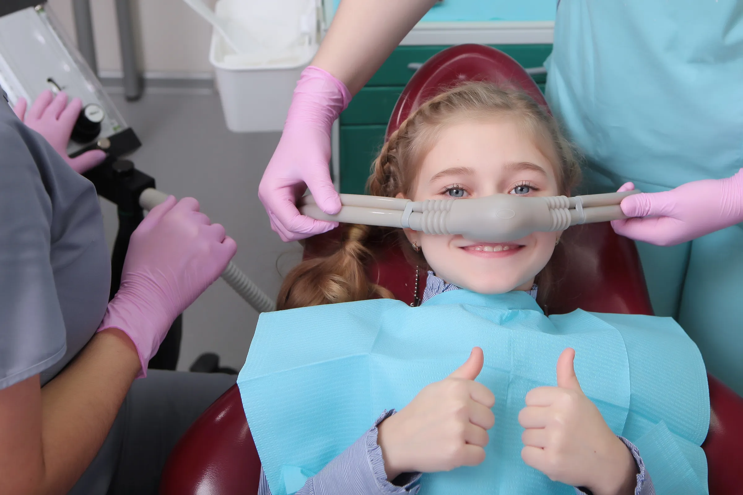 A child giving a thumbs up while wearing a nitrous oxide nasal mask