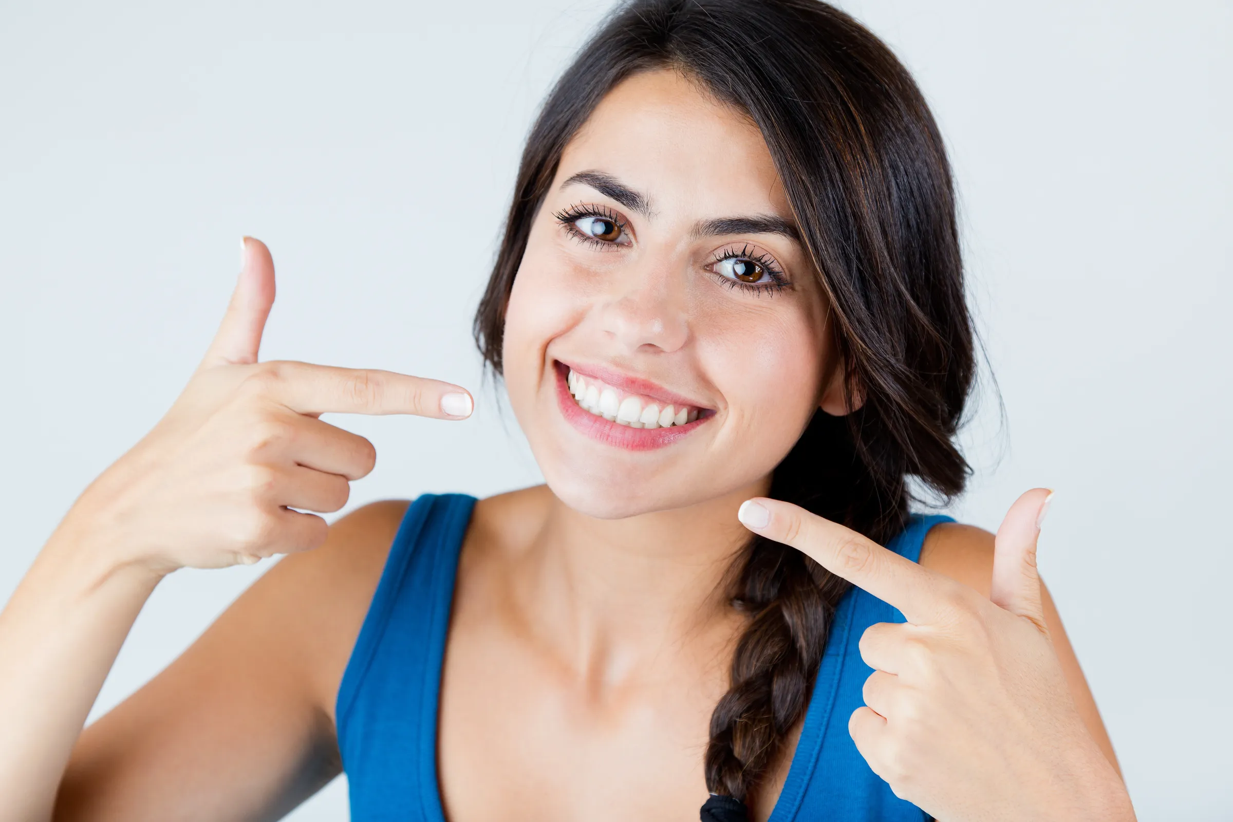 A woman pointing to her teeth after whitening