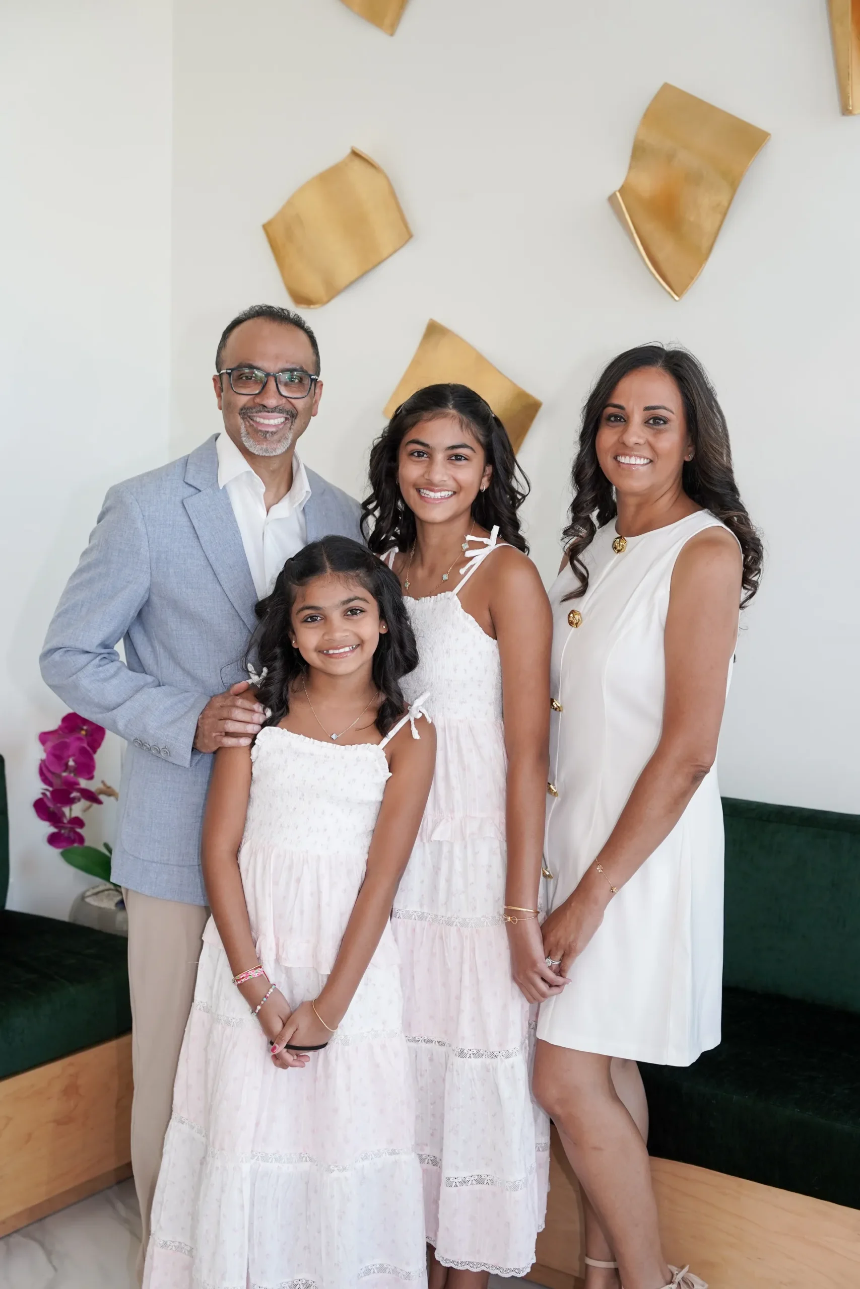 A family photographed in front of the gold-leaf feature wall at Dental Concepts