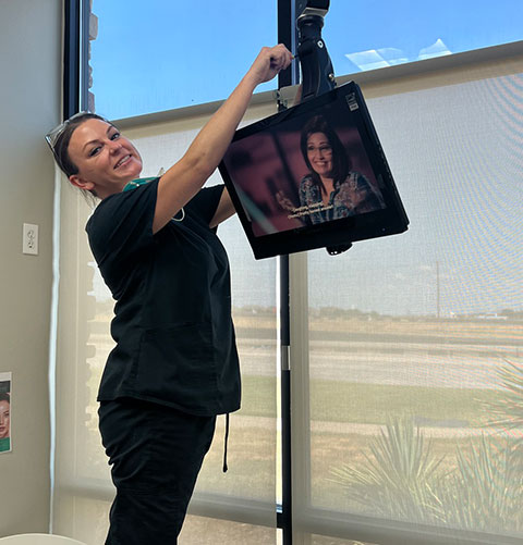 A team member reaching up to adjust a ceiling-mounted screen in a treatment room